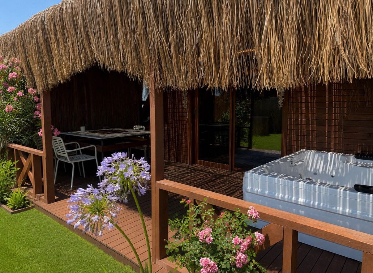 The thatched veranda of Wolf Bungalow with an outdoor jacuzzi and flowering agapanthus alongside the deck.